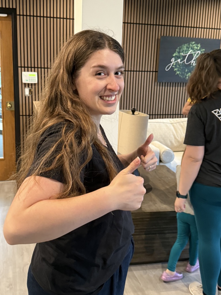 A smiling Anchor Point volunteer giving two thumbs up in the lobby.